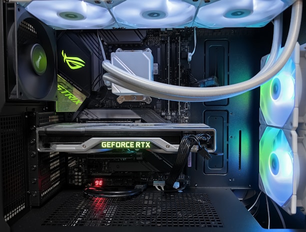 A high-end gaming or performance PC interior equipped with RGB lighting and multiple cooling fans. The graphics card prominently displayed is a GeForce RTX model, with branding visible. The setup includes neatly managed cables and a liquid cooling system.